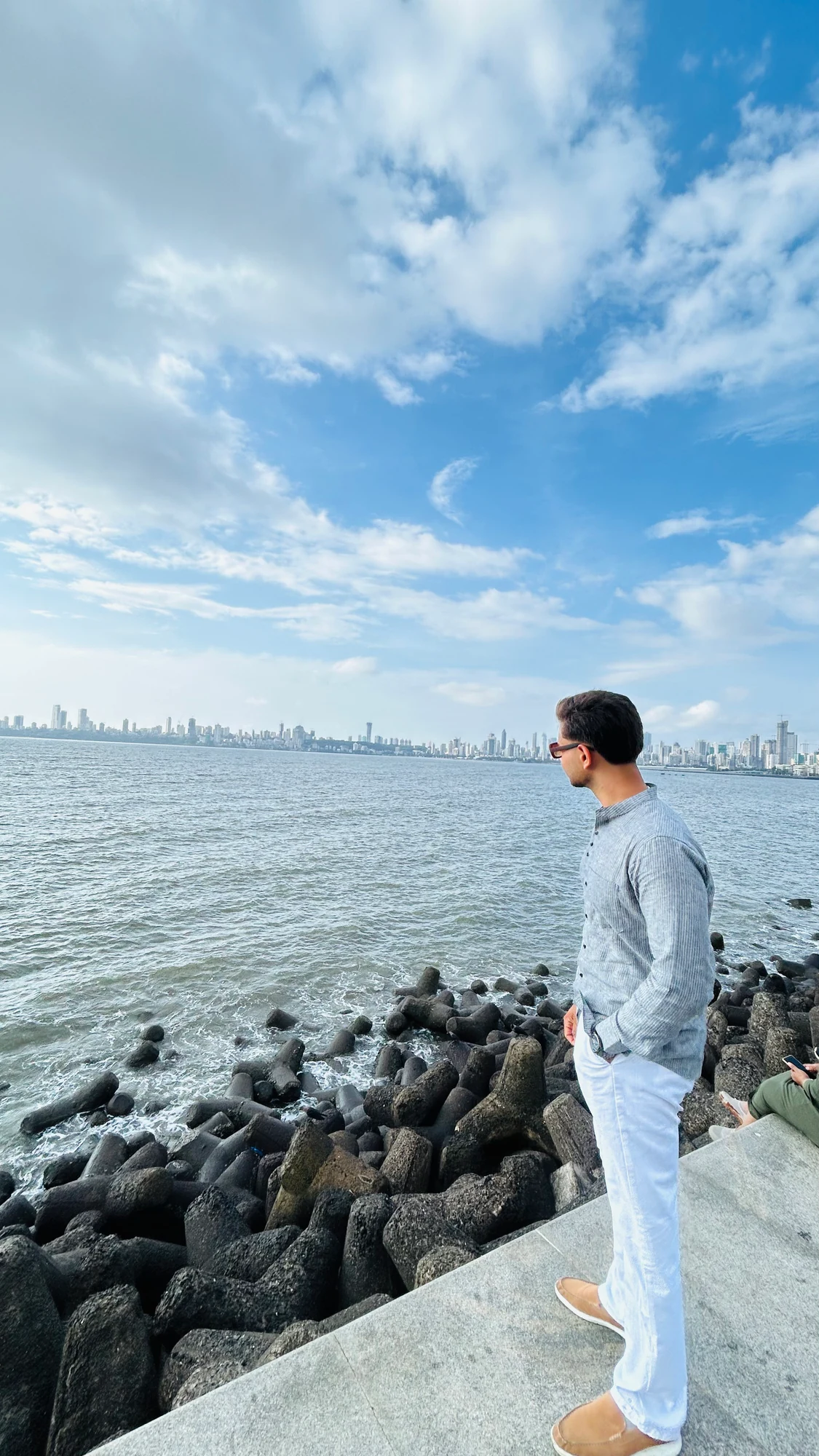 Pratham Sukhadia looking across the sea toward a distant city skyline
